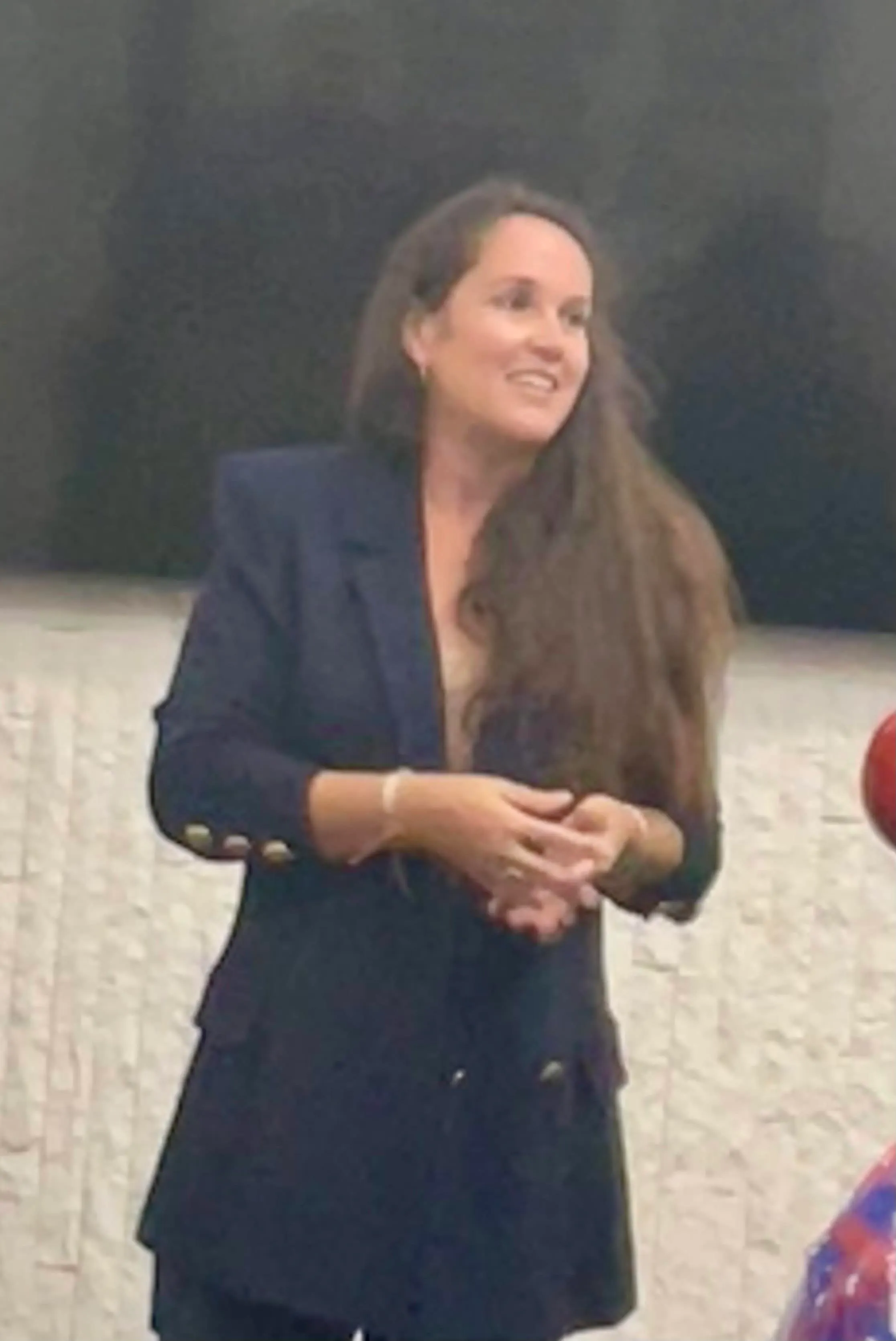 Candid photo of Andrea McGee smiling in a dark blazer at an indoor event