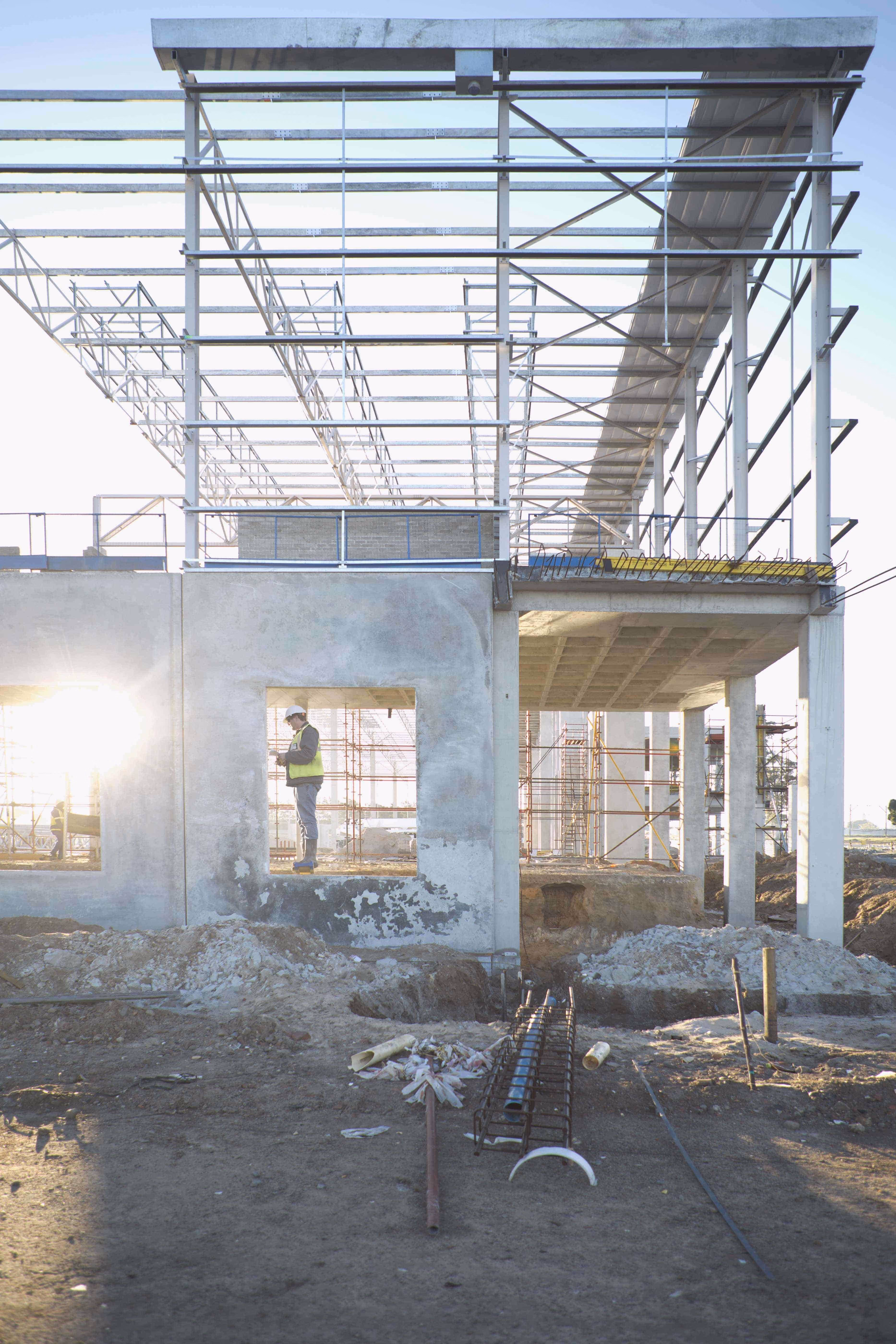 Worker in a hard hat inspecting an open concrete building frame under construction