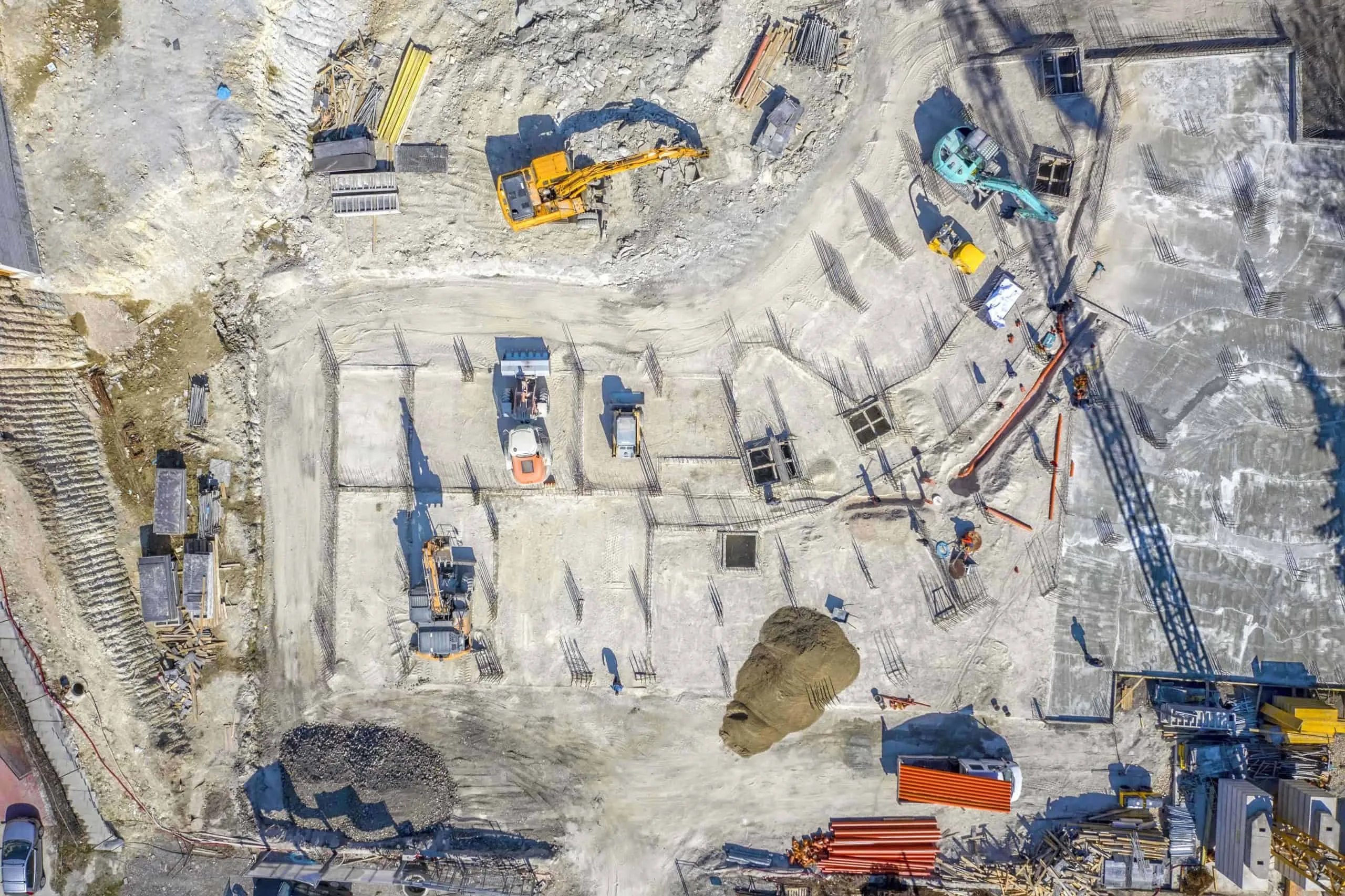 Aerial view of a building foundation under construction with excavators and formwork