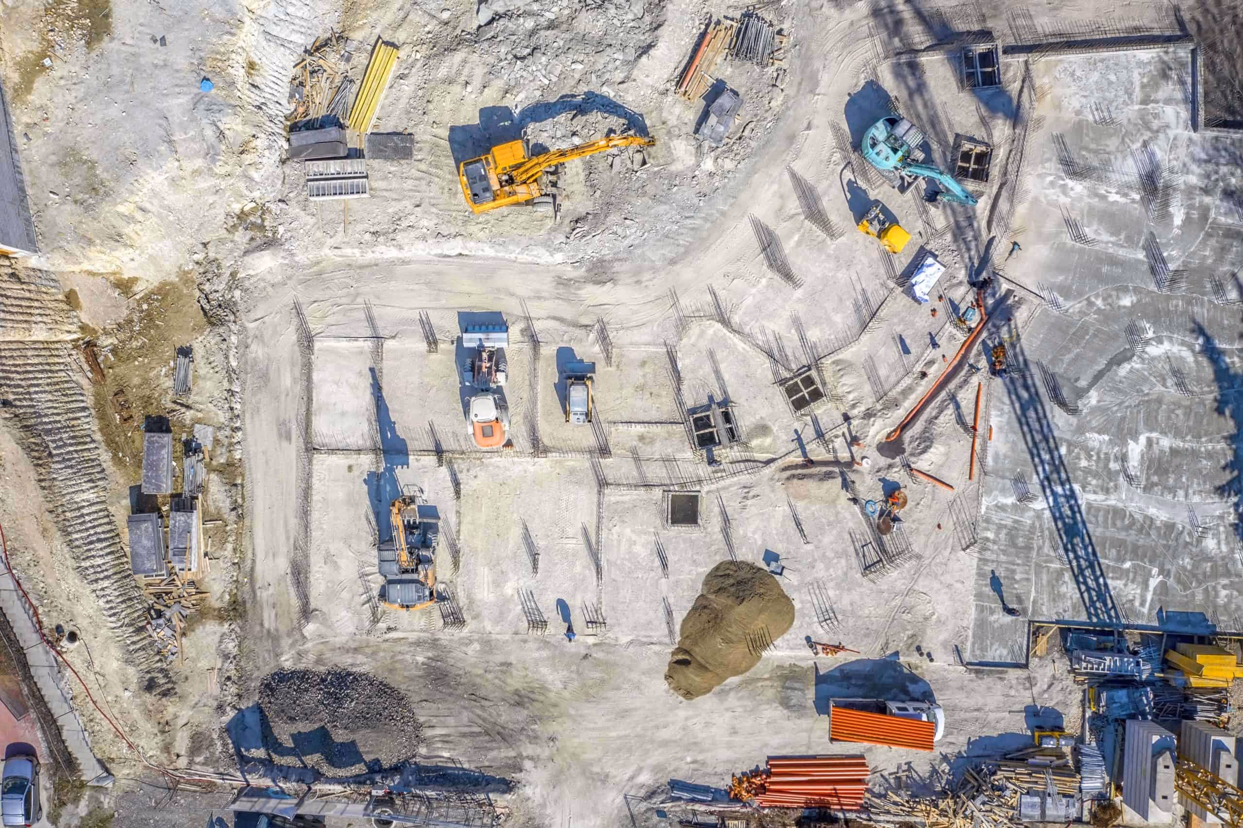 Aerial view of a building foundation under construction with excavators and formwork