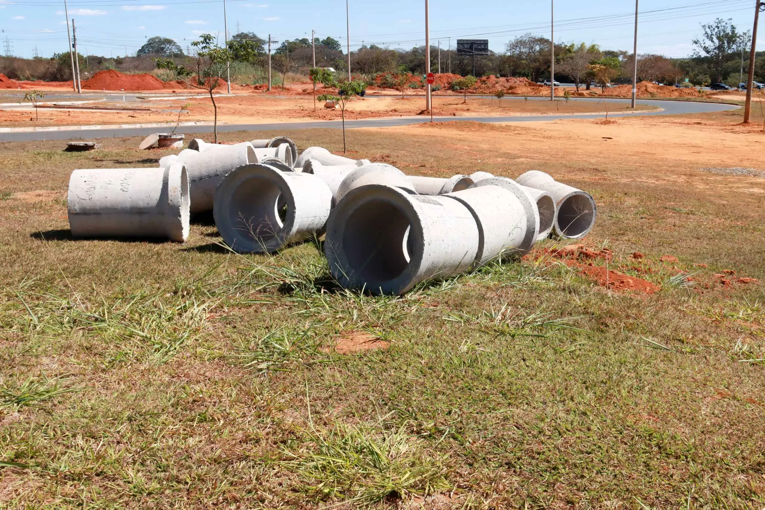 Large concrete sewer pipe sections laid out on grass at a construction site