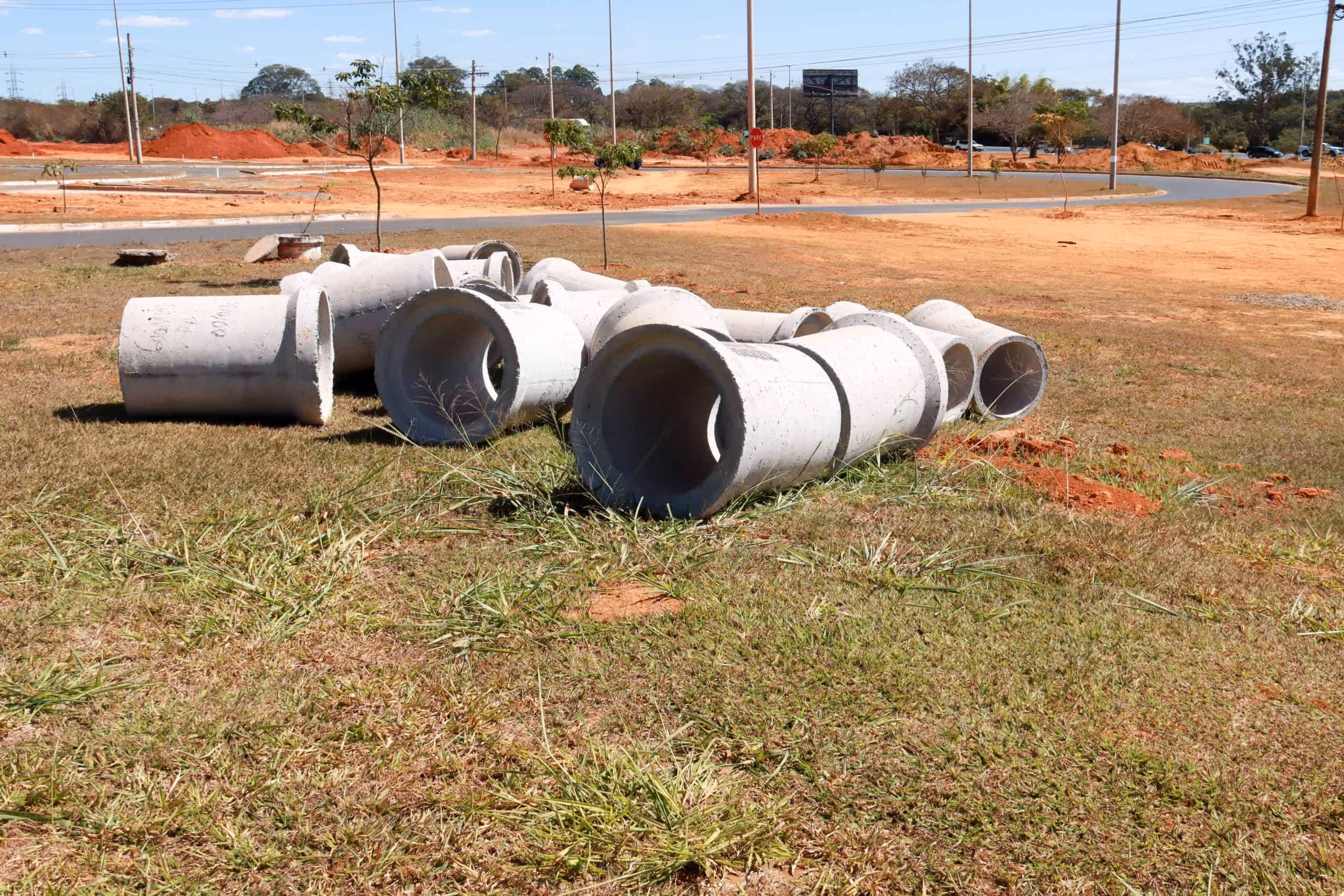 Large concrete sewer pipe sections laid out on grass at a construction site